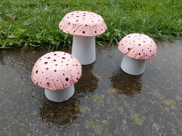 Set of 3 apricot coloured concrete mushrooms.