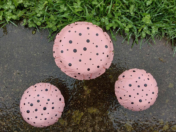 Set of 3 apricot coloured concrete mushrooms.
