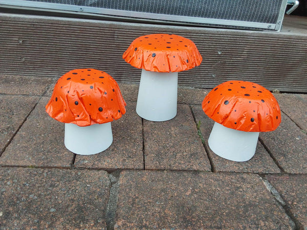 Set of 3 orange concrete mushrooms.