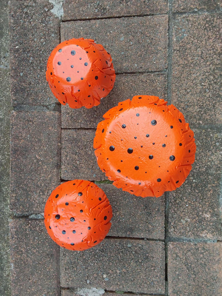 Set of 3 orange concrete mushrooms.
