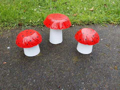 Set of 3 red coloured concrete mushrooms.